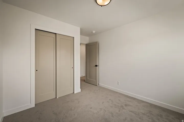 Neutral wall color, carpet flooring, flush mount ceiling light, sliding closet doors, and single panel interior door