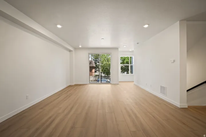Recessed lighting, wood-finish flooring, white walls, large sliding glass door, and a window