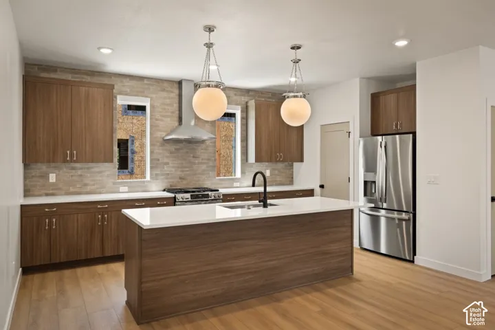 Kitchen featuring wood-finish cabinetry, stainless steel appliances, brick-style backsplash, and a center island with a black faucet