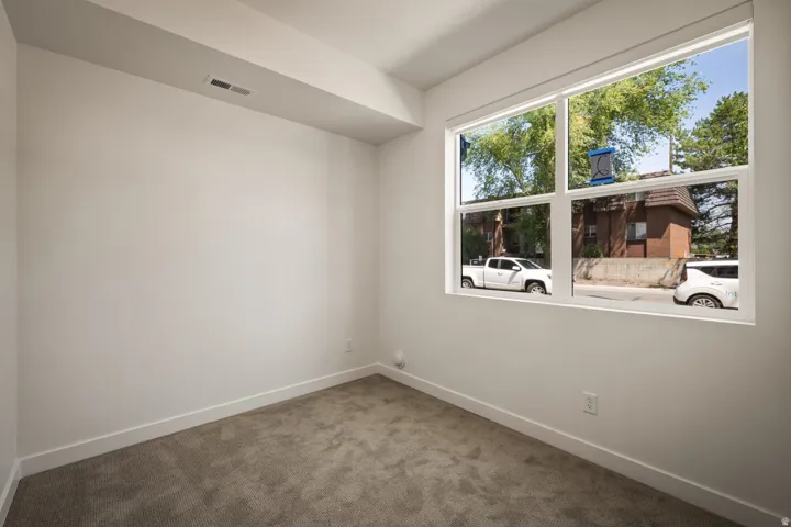 Large picture window, white trim, textured carpet flooring, white walls, recessed ceiling fixture