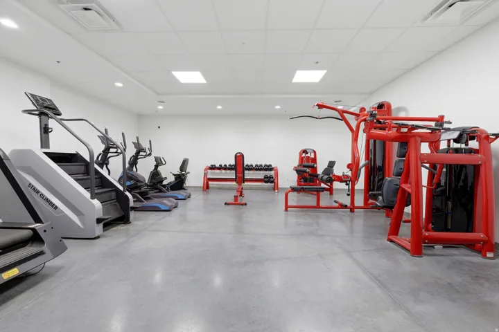 Spacious fitness area featuring cardio equipment, strength training machines, and free weights