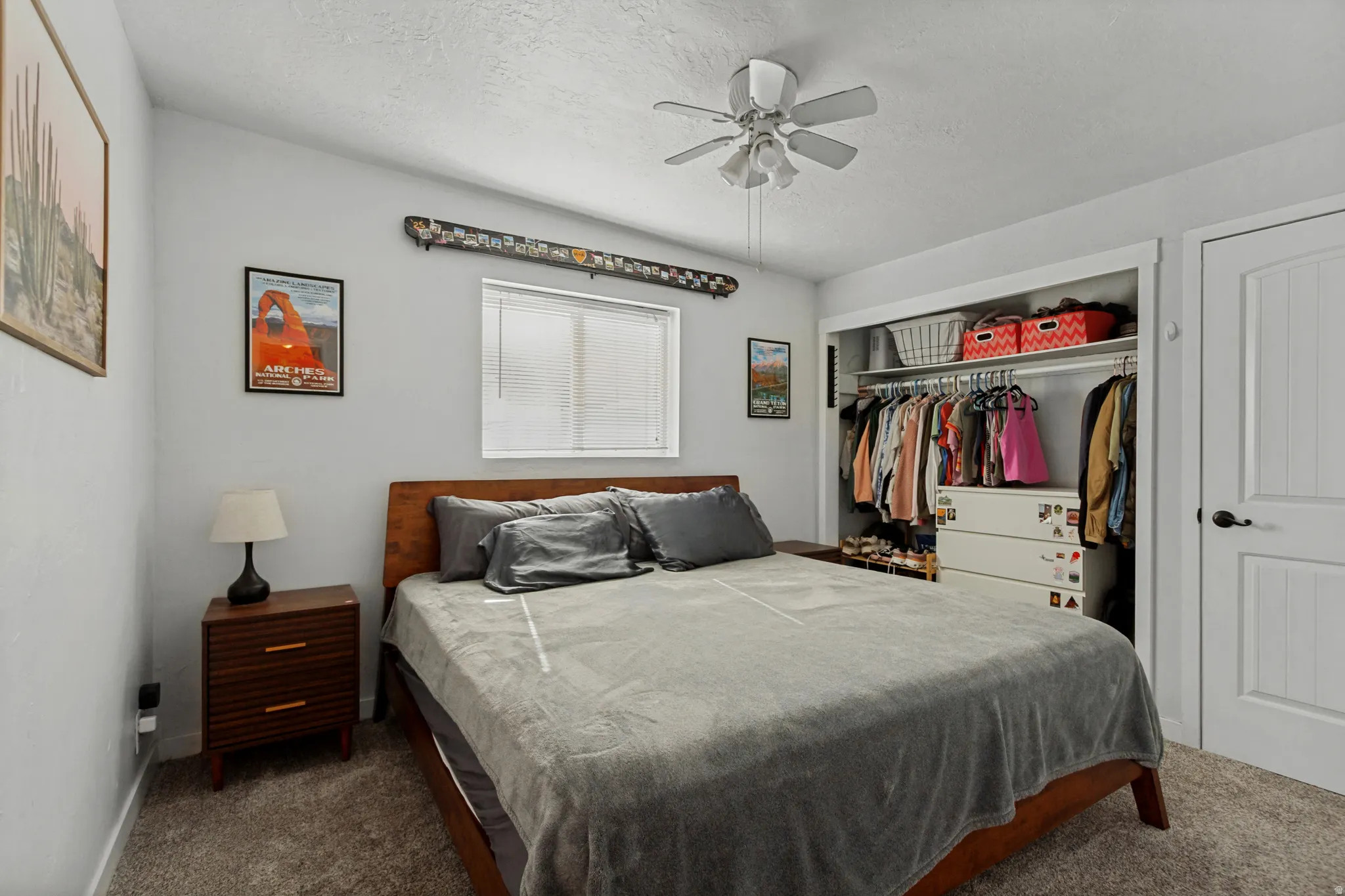 Integrated ceiling fan, carpet flooring, window with blinds, built-in closet storage, and a paneled interior door