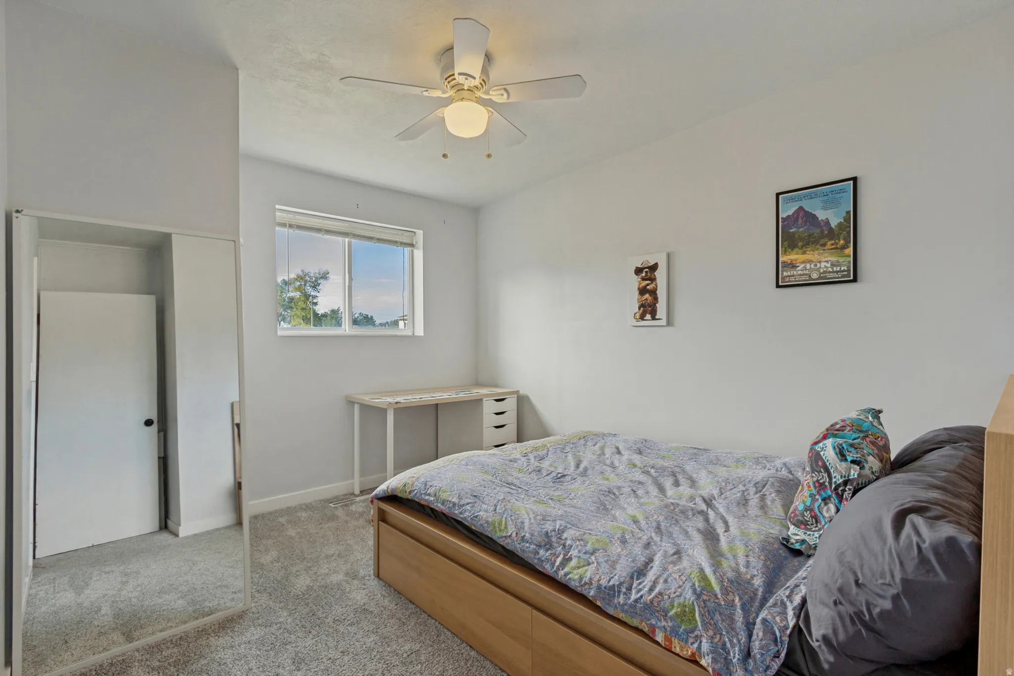 Recessed window with a white frame, overhead ceiling fan with lighting, light-toned carpeting, and a built-in closet with mirrored sliding doors