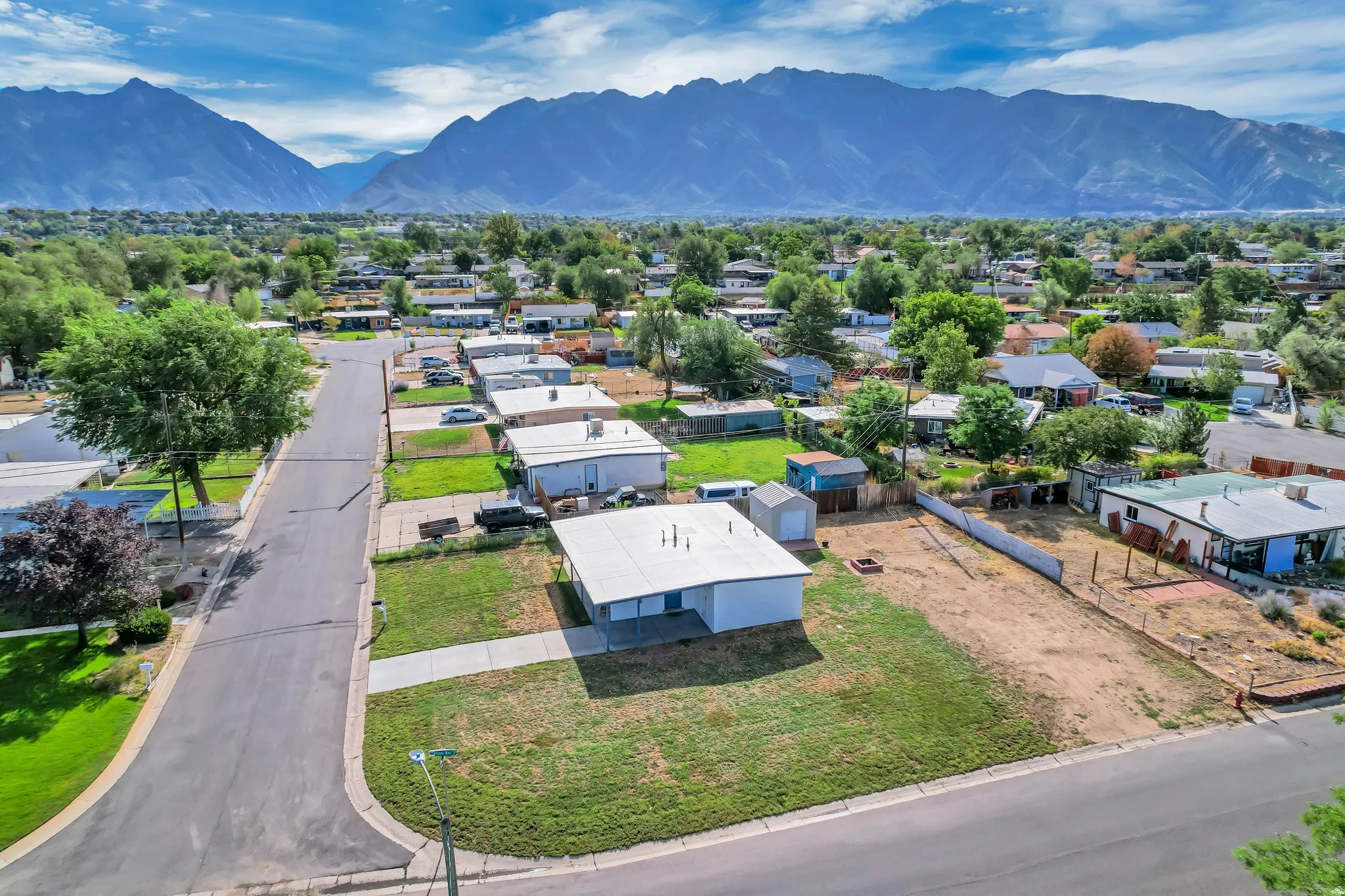 Expansive residential lot with a paved street frontage, green lawn, and a mountain backdrop