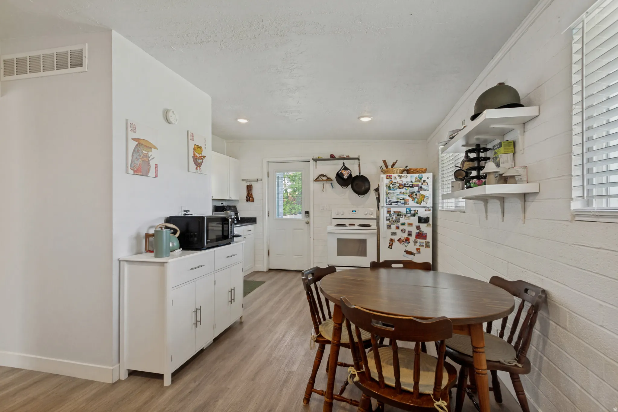 Light wood-finish flooring, white walls, recessed ceiling lights, and white built-in cabinetry