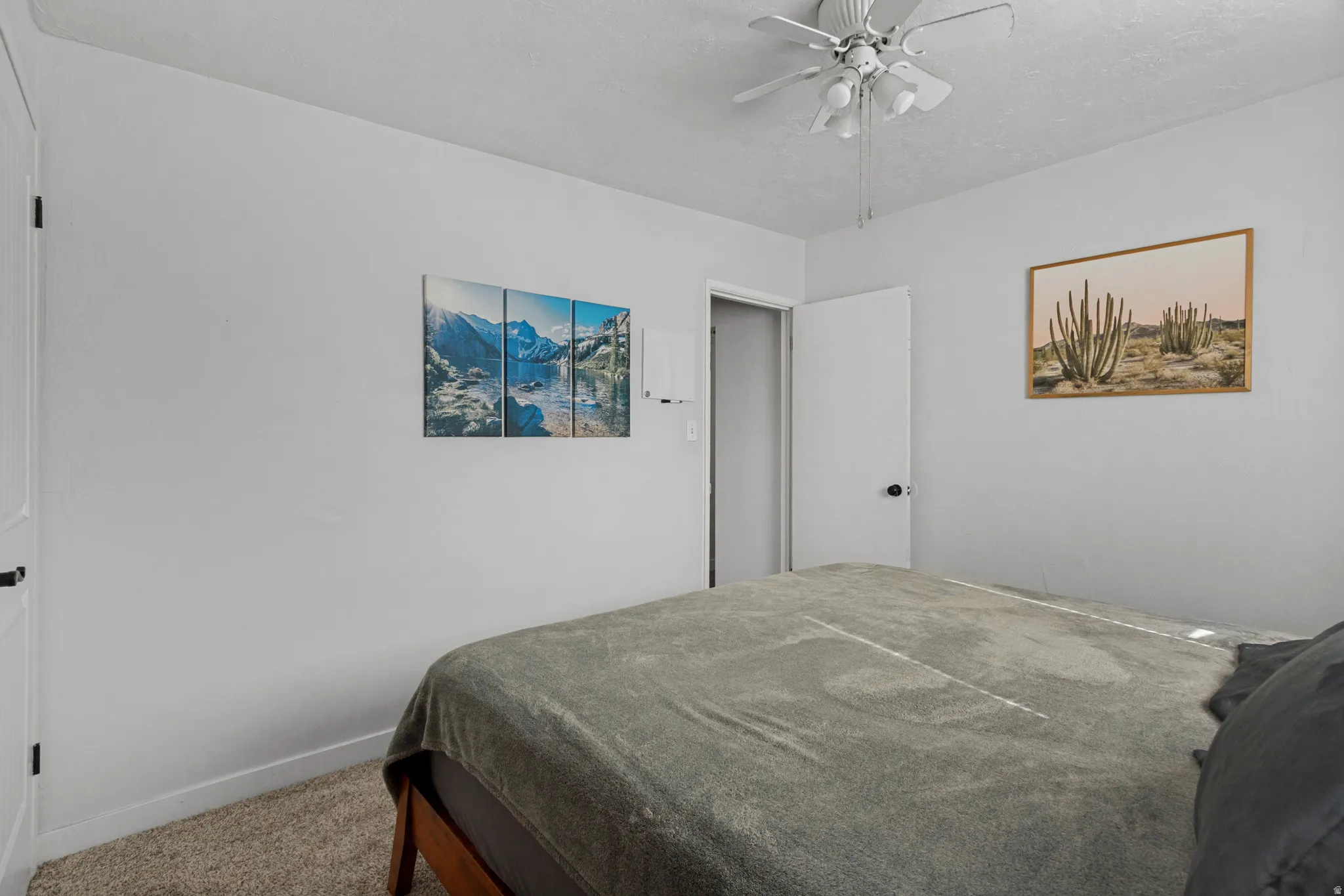 Textured carpeting, white walls, white ceiling fan with integrated lighting, and a white door with a black doorknob