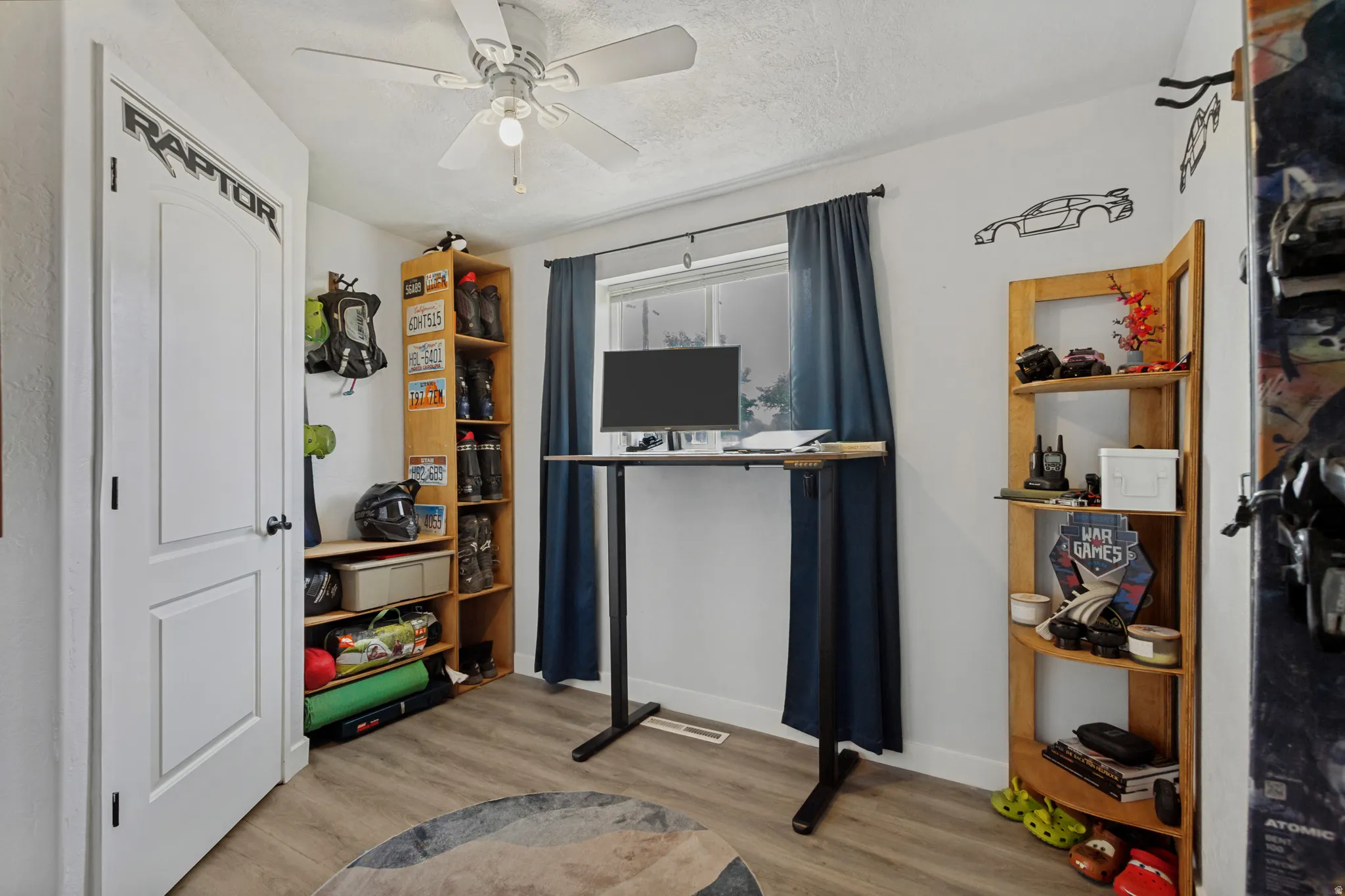 Wood-finish flooring with white walls and a ceiling fan