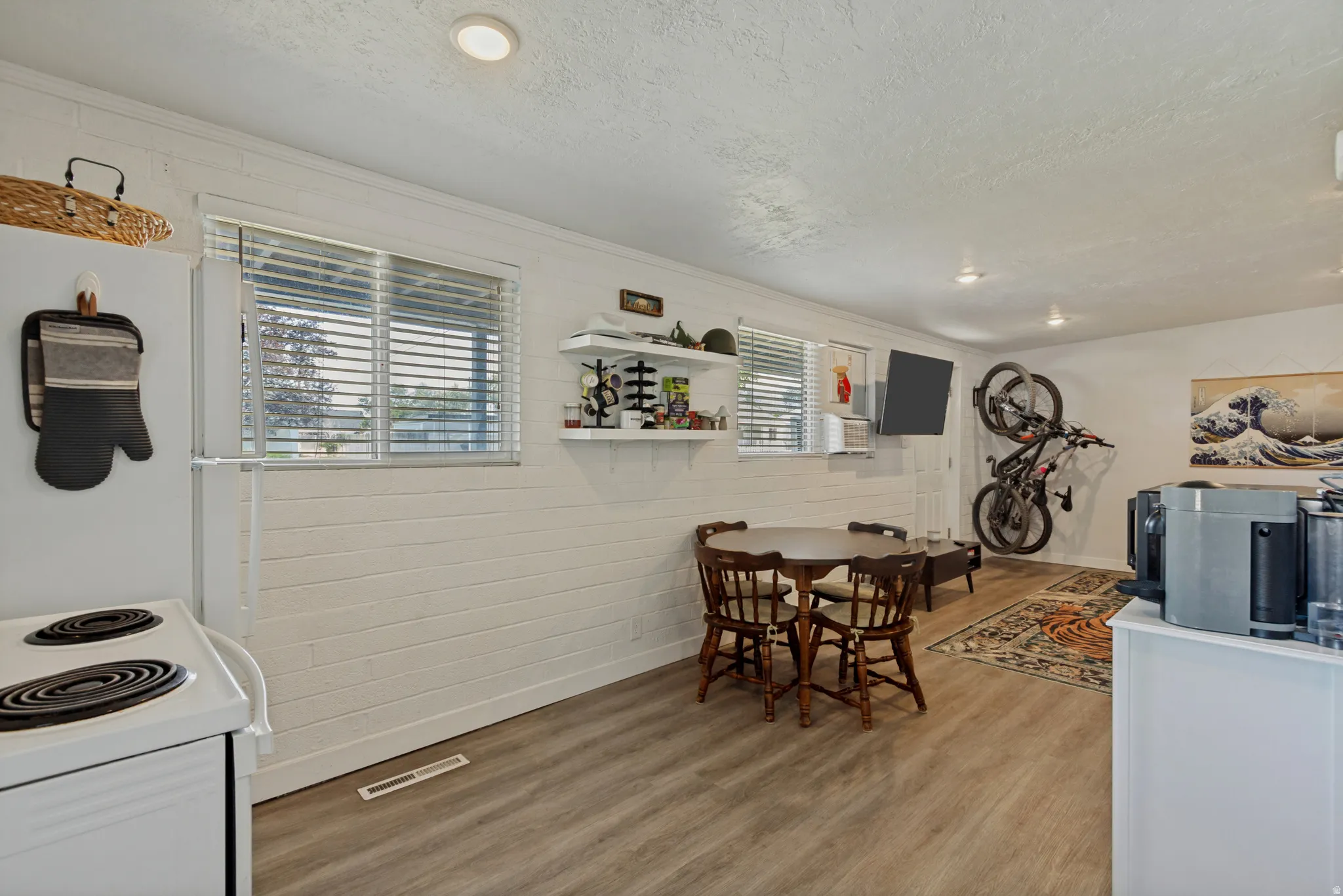 Wood-finish flooring throughout, white painted walls, recessed lighting, and two windows with blinds