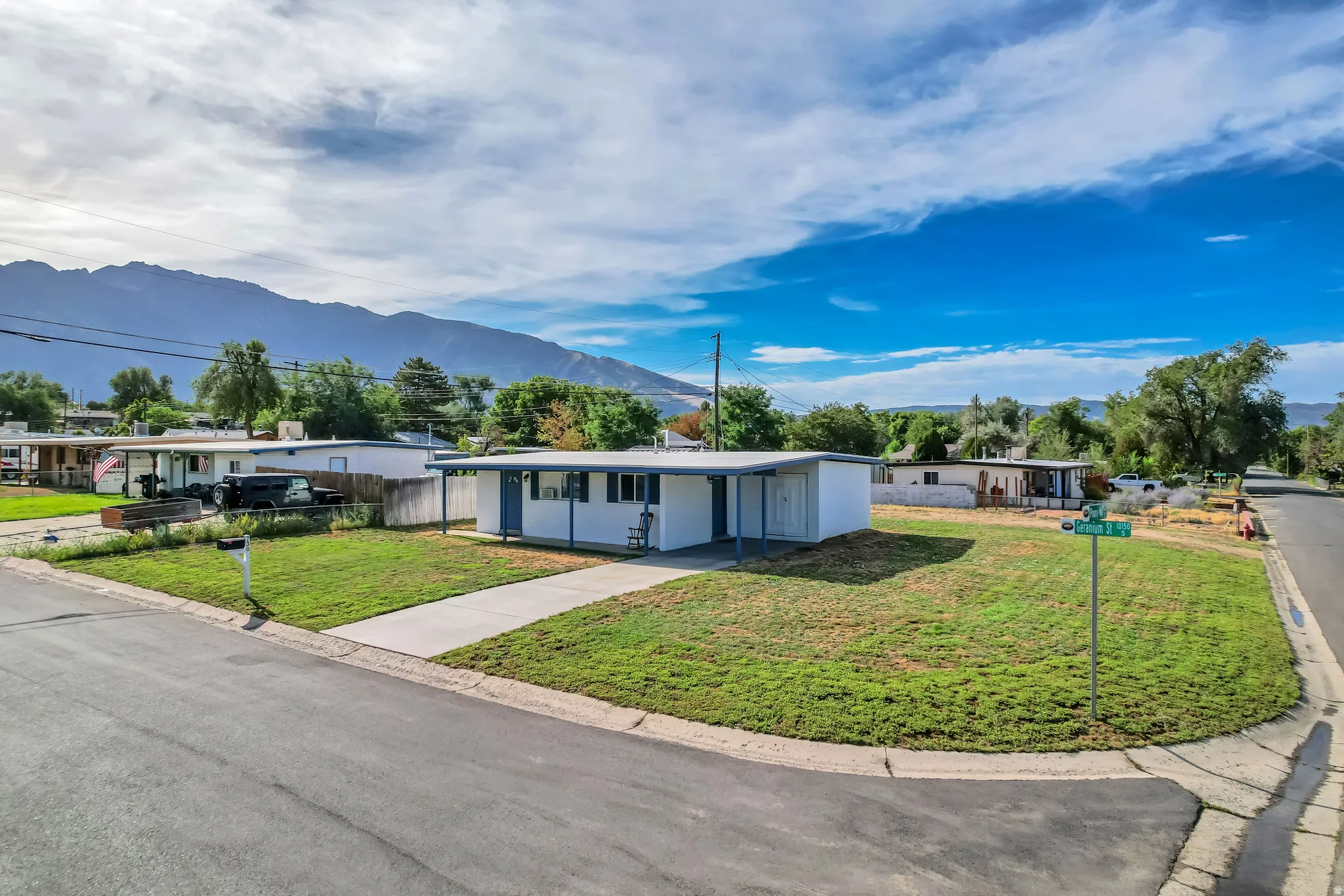 Corner lot property with a flat roof, a covered front porch, and a concrete driveway