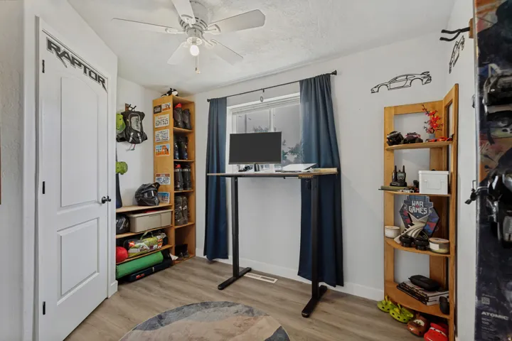 Wood-finish flooring with white walls and a ceiling fan