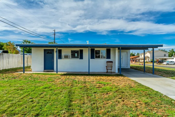 White exterior with blue trim and shutters, covered entryway, and an attached carport