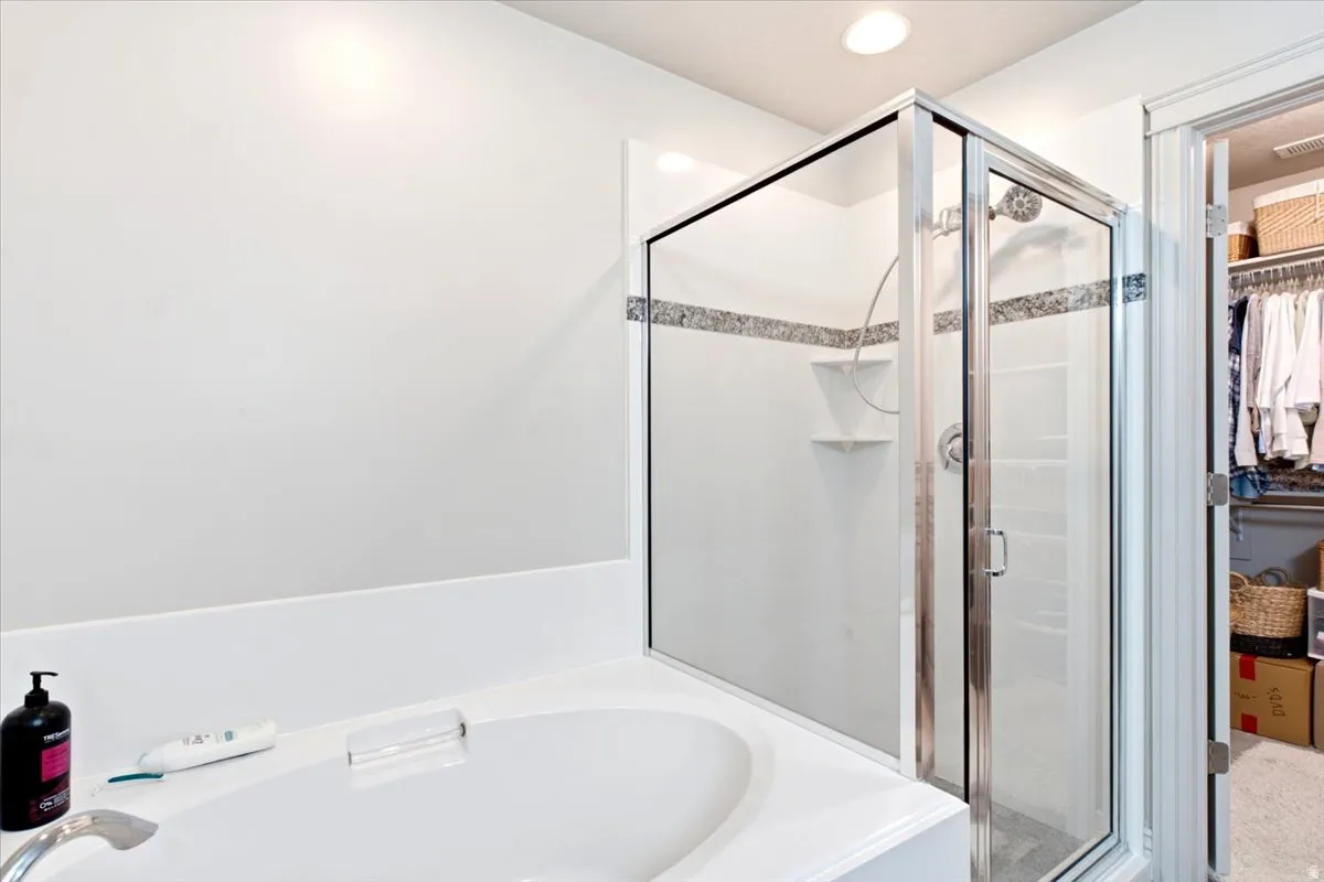 Built-in soaking tub, glass-enclosed shower with tile accent band, and recessed lighting