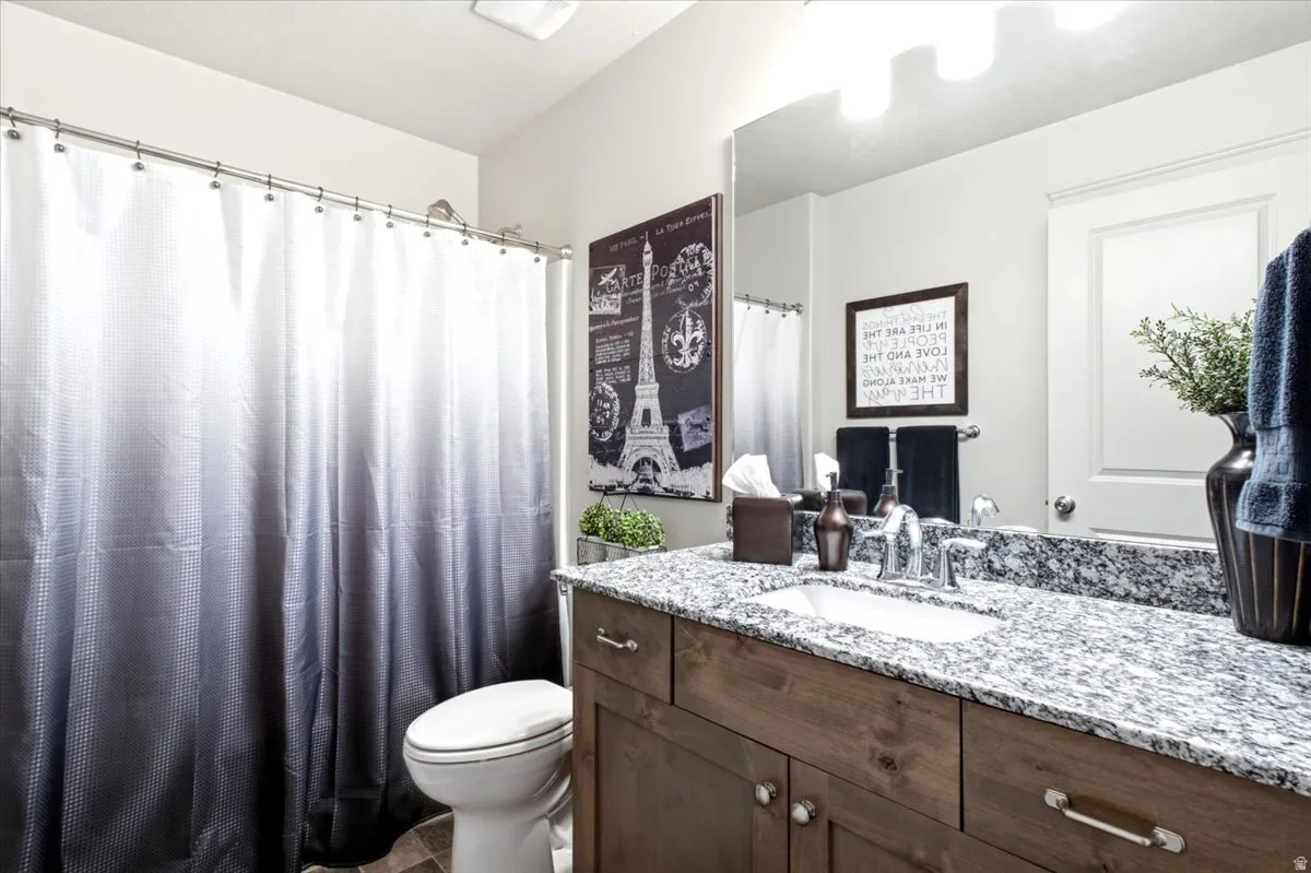 Vanity with granite countertop and integrated sink, chrome faucet, and wood-finish cabinetry