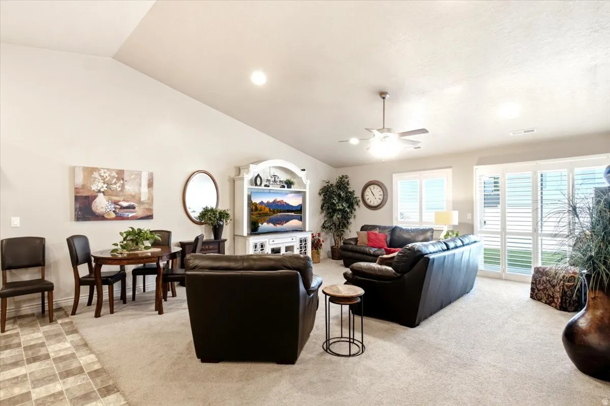Vaulted ceiling, recessed lighting, ceiling fan, carpet flooring, and white plantation shutters on windows and sliding glass door