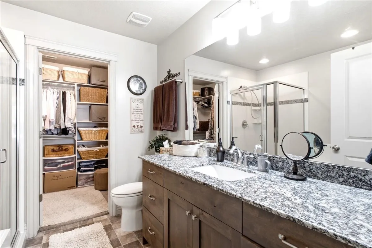Expansive vanity with a single basin sink, speckled stone countertop, and wood-finish cabinetry