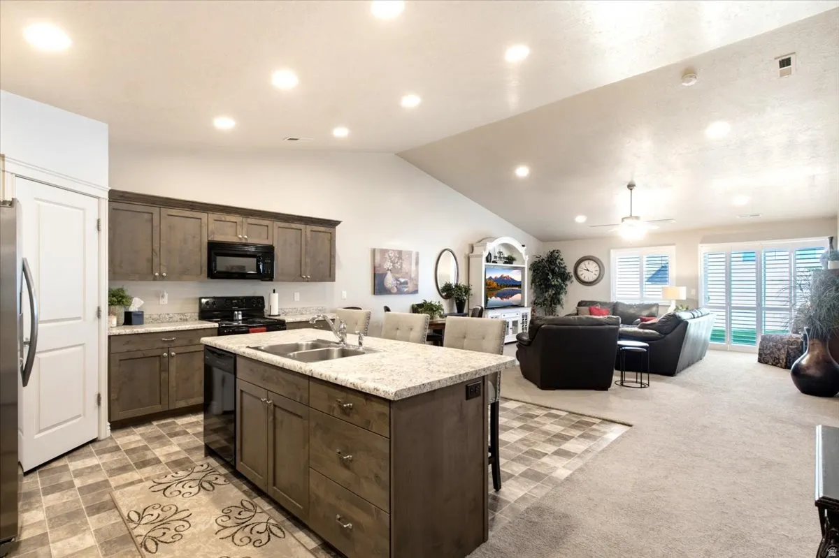 Kitchen with wood-finish cabinetry, granite countertops, and black appliances