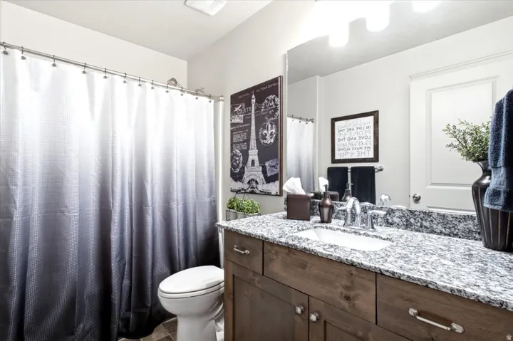Vanity with granite countertop and integrated sink, chrome faucet, and wood-finish cabinetry