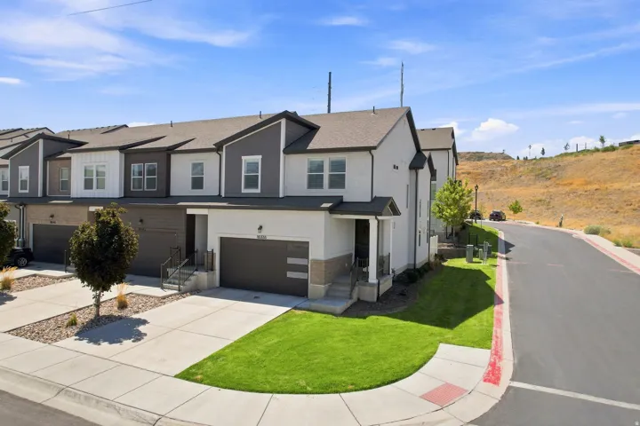 Multi-level townhome with a two-tone exterior, attached two-car garage, and a covered entry