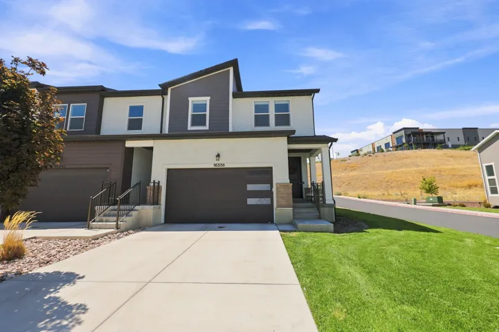Contemporary exterior with two-tone stucco and siding, attached garage, concrete driveway, and a covered entry