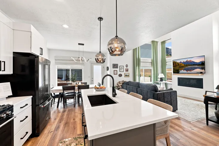 Open-concept living area with wood-finish flooring, a contemporary fireplace, and high ceilings