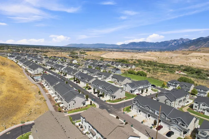 Residential development featuring multiple townhome-style residences, paved streets, and a mountainous backdrop