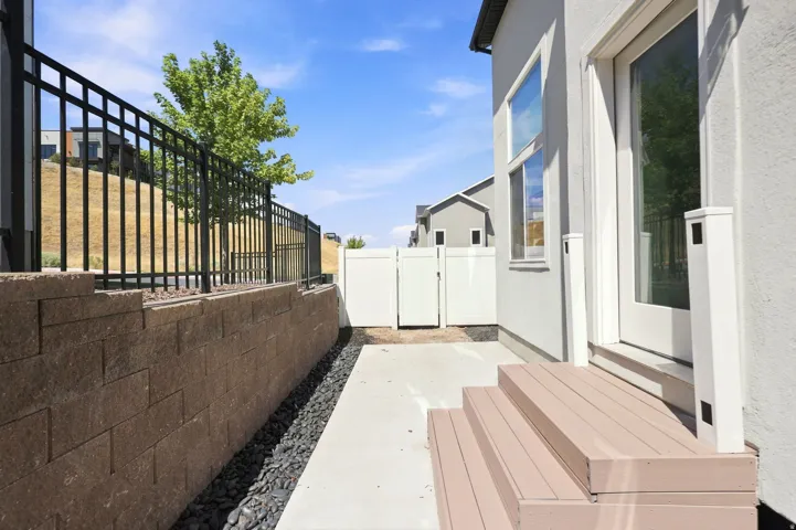 Walk-out patio with composite steps, concrete pathway, and a retaining wall