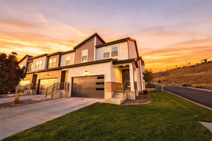 Modern townhome with attached garage, landscaped lawn, and a covered entry