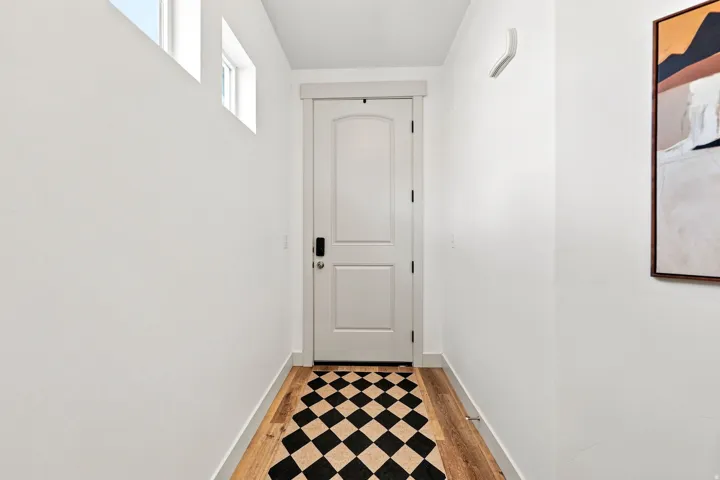 Wood-finish flooring with a white door featuring panel detailing