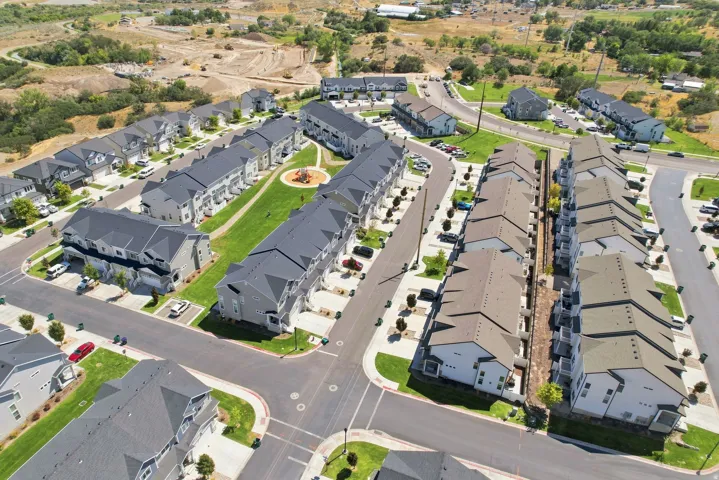 Modern townhome community featuring varied exterior finishes, paved roadways, and landscaped green spaces