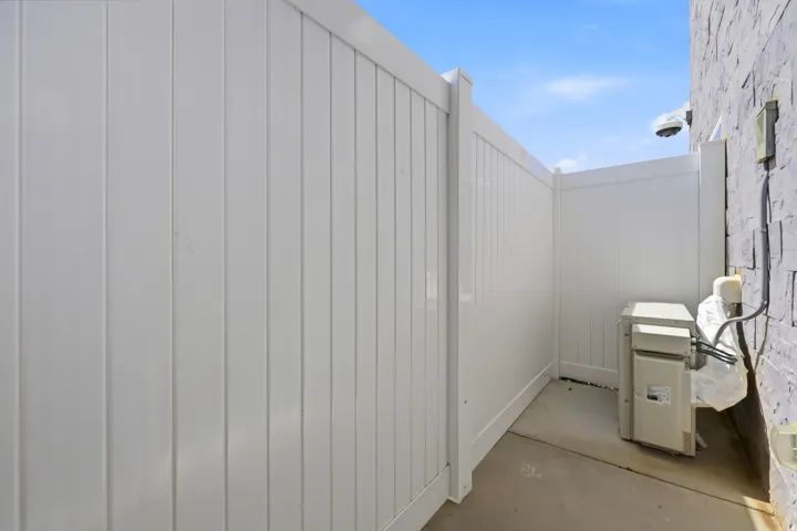White panel fencing enclosing an outdoor utility area with a concrete pad