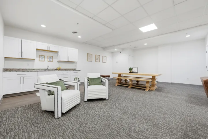 Contemporary kitchenette with white shaker cabinetry, granite-finish countertops, and a stainless steel sink