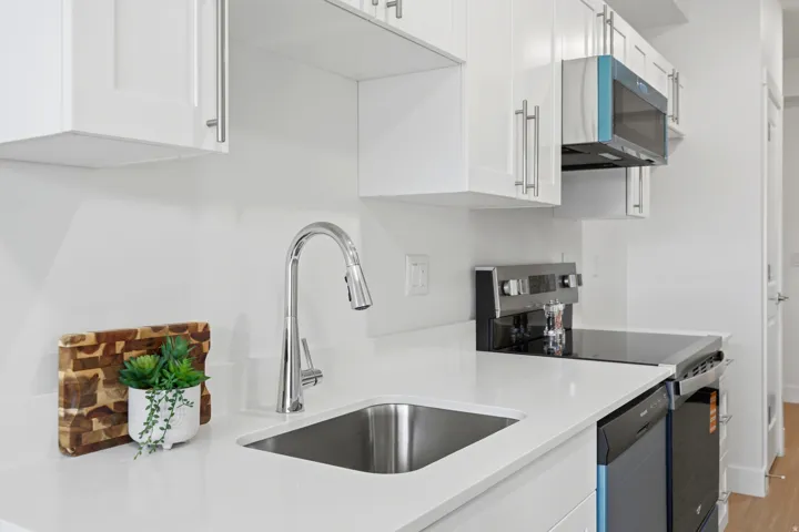 White cabinetry, stainless steel sink, chrome faucet, white countertops, and stainless steel appliances