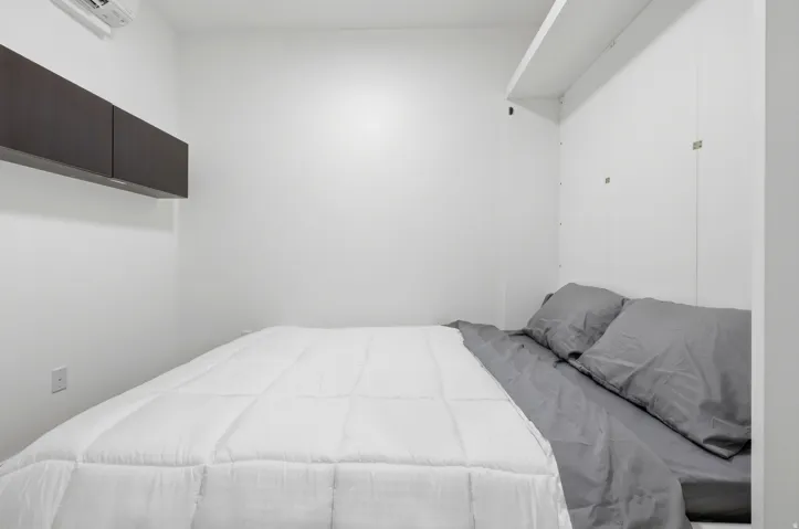 Wall-mounted cabinetry, integrated shelving, and a wall-mounted air conditioning unit