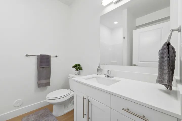 White vanity with brushed nickel hardware, integrated sink, and a large wall-mounted mirror