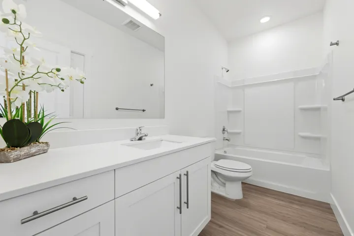 White vanity with brushed nickel hardware, integrated sink, and a large wall-mounted mirror