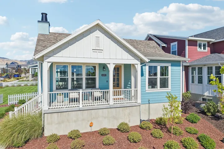 Front porch with white railings, a light wood-finish door, and prominent windows