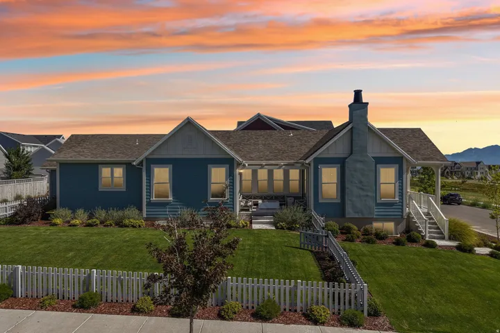 Siding exterior, gabled roofline, stone chimney, covered porch, and well-maintained lawn