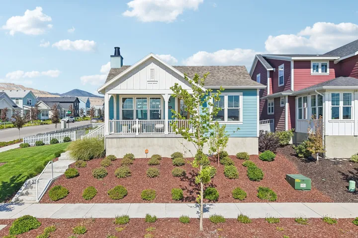 Craftsman-style home with light blue siding, a white front porch with railings, and a peaked roofline