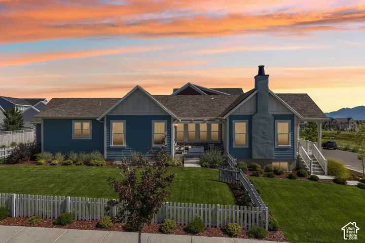 Siding exterior, gabled roofline, stone chimney, covered porch, and well-maintained lawn