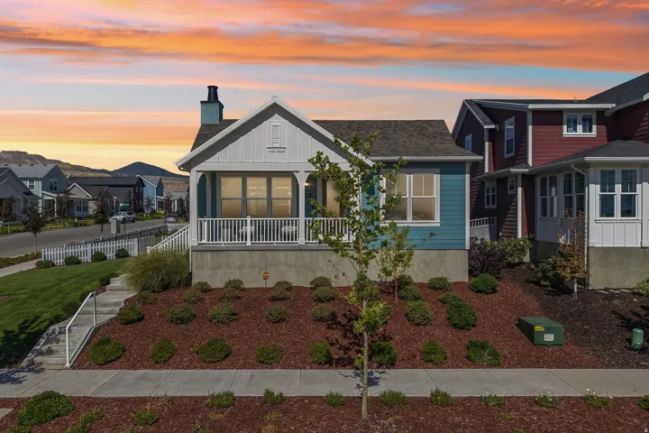 Craftsman-style home featuring a covered front porch with white railings, blue siding, and white trim accents