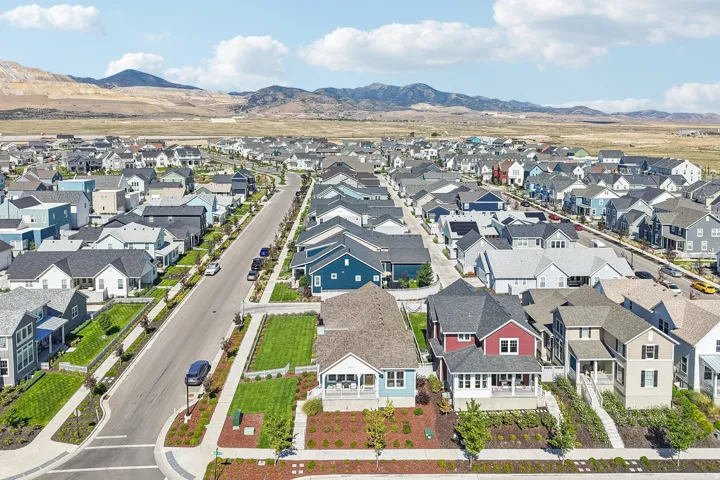 Expansive residential community with varied architectural styles, manicured landscaping, and mountain backdrops
