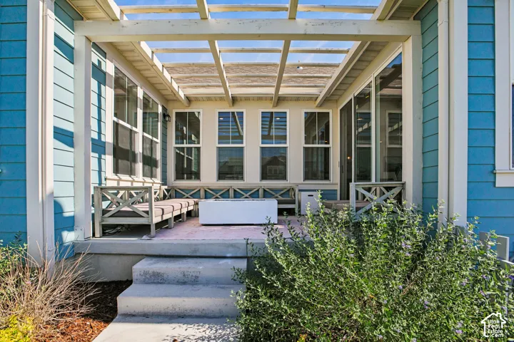 Expansive outdoor patio featuring a slatted pergola, concrete steps, and a built-in bench with decorative cross-bracing
