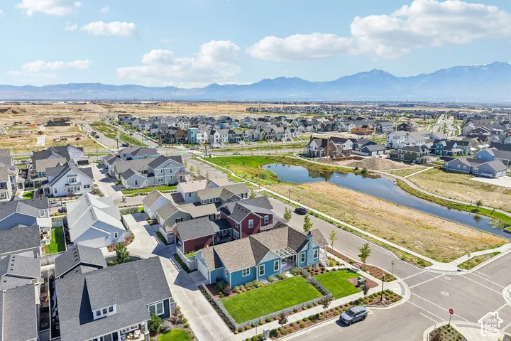 Aerial perspective of a developed neighborhood with diverse architectural styles, a central pond feature, and a backdrop of distant mountains