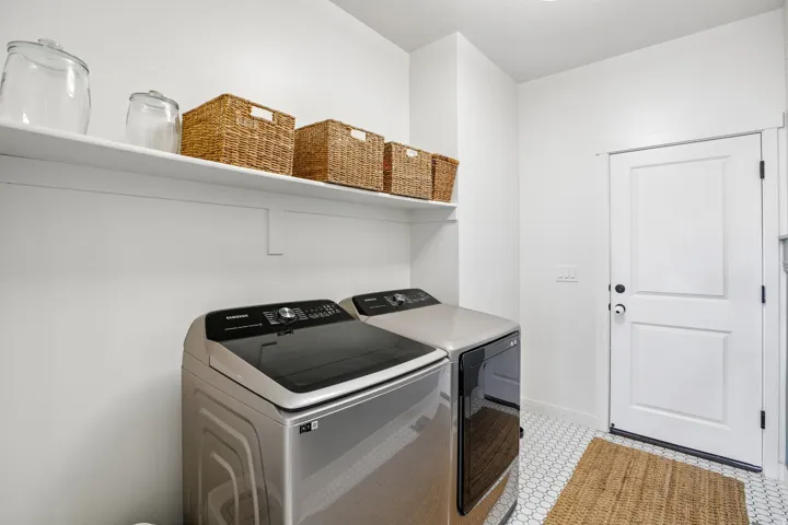 Laundry area with white walls, white shelving, and hexagonal tile flooring