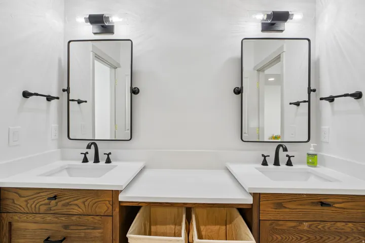 Dual vanity with undermount sinks, wood-finish cabinetry, white countertops, and matte black fixtures