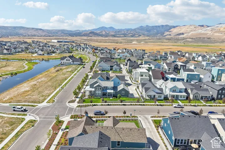 Aerial perspective showcasing a residential community with diverse home styles, a prominent waterway, and distant mountain scenery