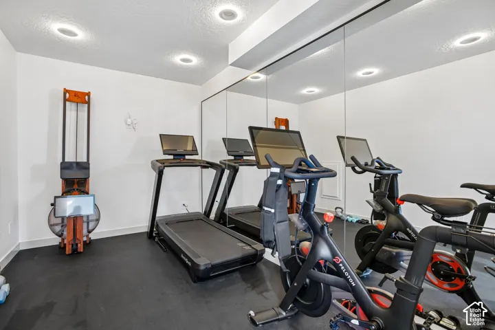 Dedicated fitness area featuring wall-to-wall mirrors, recessed lighting, and durable rubber flooring