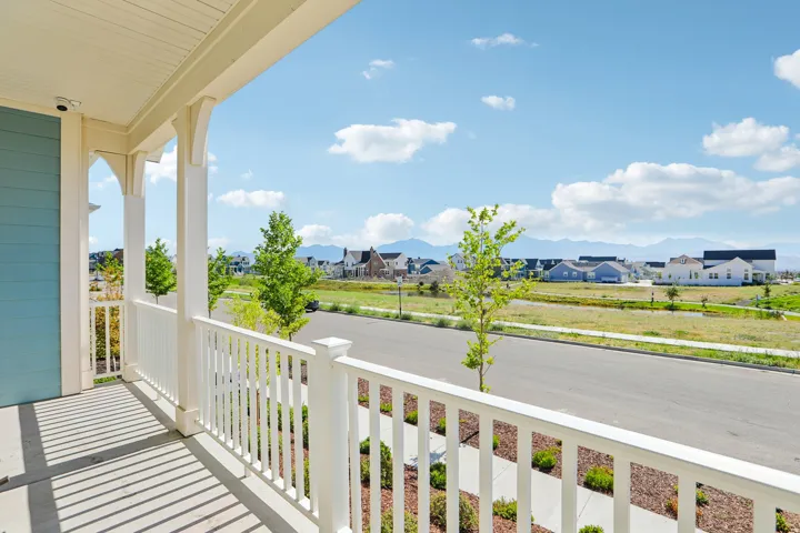 Covered front porch with white railings, light blue siding, and a concrete floor