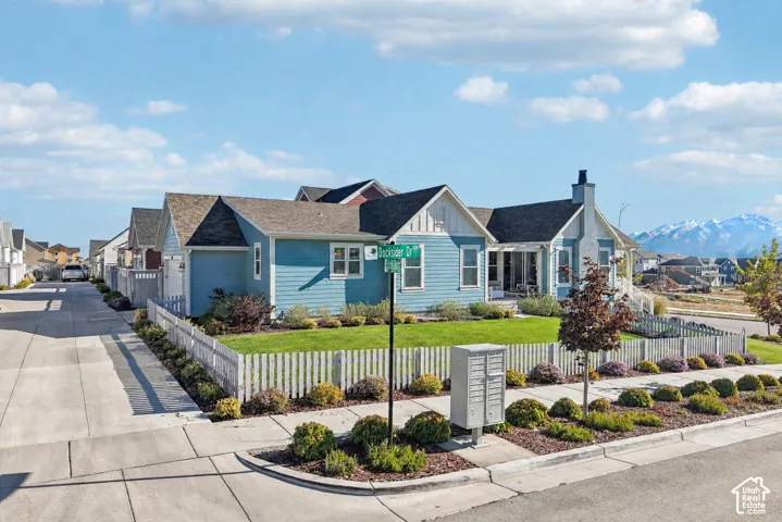 Single-story residence featuring blue horizontal siding, vertical board-and-batten accents, a pitched roof, an exterior chimney, and a picket-fenced yard