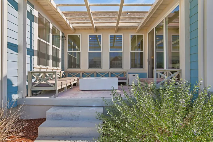 Covered patio with a slatted pergola, siding exterior, and multiple windows